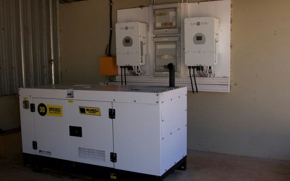 Un grupo electrógeno de emergencia con inversores montados en la pared detrás