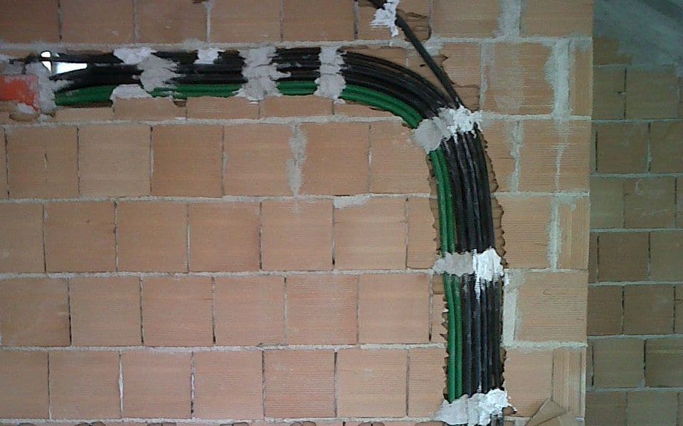 مواسير وكابلات كهربائية ممدودة على جدار طوب في مبنى قيد الإنشاء