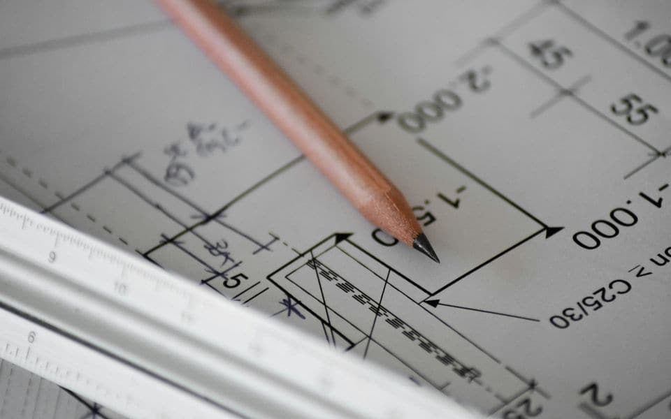 Architectural blueprints and a drafting pencil laid out on a workspace table
