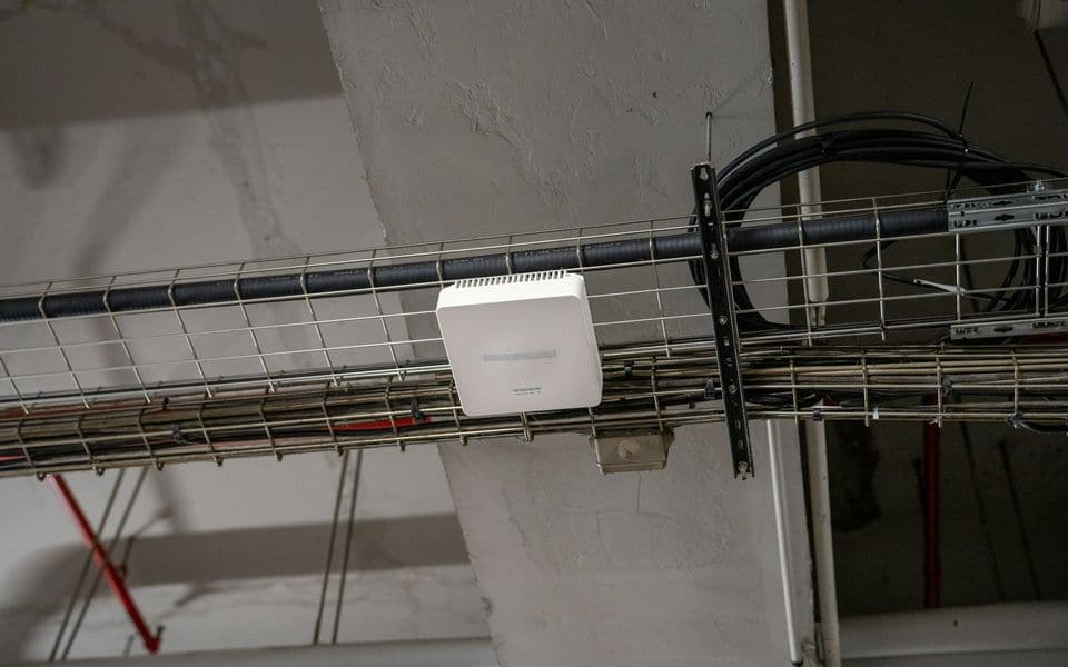 An enterprise Wi-Fi access point mounted on a ceiling cable tray
